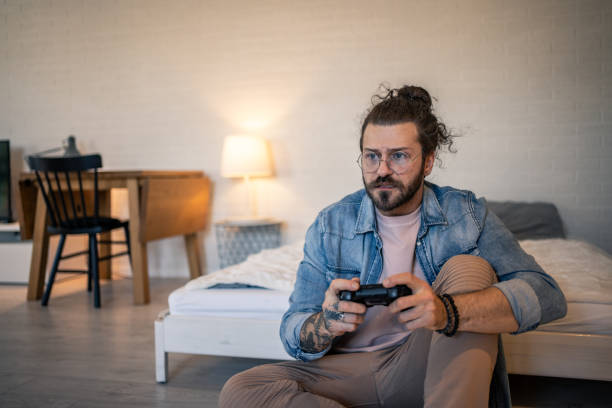 istock Focused young man playing video games in his bedroom 2205929018