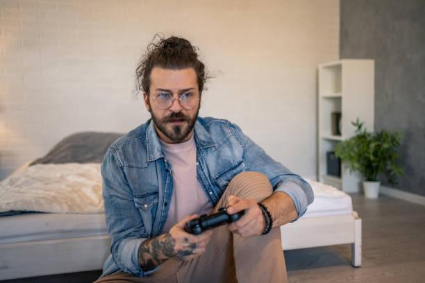 istock Focused young man playing video games in his bedroom 2205929024