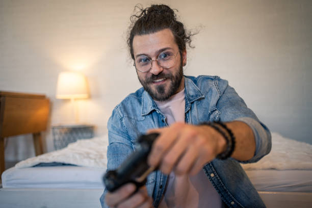 istock Young man playing videogames in his bedroom 2205929041