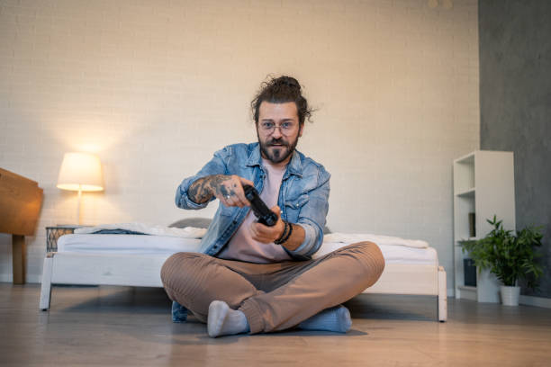 Young man playing videogames sitting on the floor in his bedroom