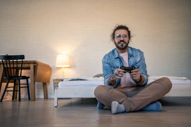istock Young man playing videogames sitting on the floor in his bedroom 2205929063