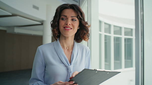 istock Smiling boss reviewing documents on clipboard walking modern office closeup. 2205930488
