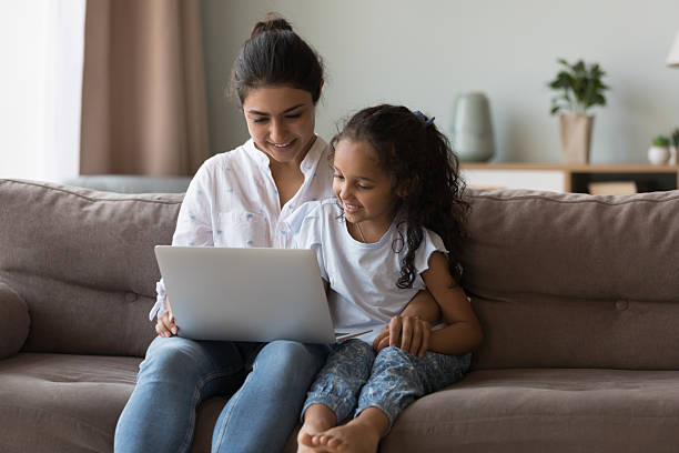 istock Cute girl using laptop sit on sofa with loving mom 2205930994