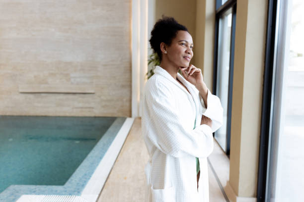 istock Woman in white bathrobe gazing outside at a luxurious indoor spa setting 2205931258