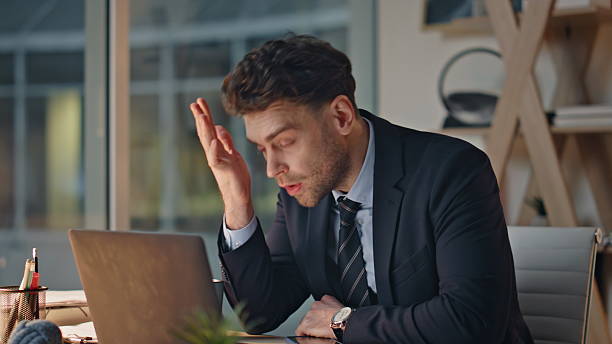 istock Frustrated professional holding head sitting dark office showing stress closeup. 2205935815