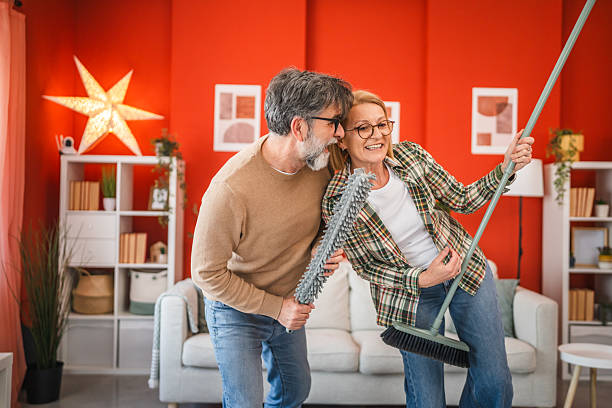 istock mature couple have fun while use cleaning tool like music instruments 2205936111