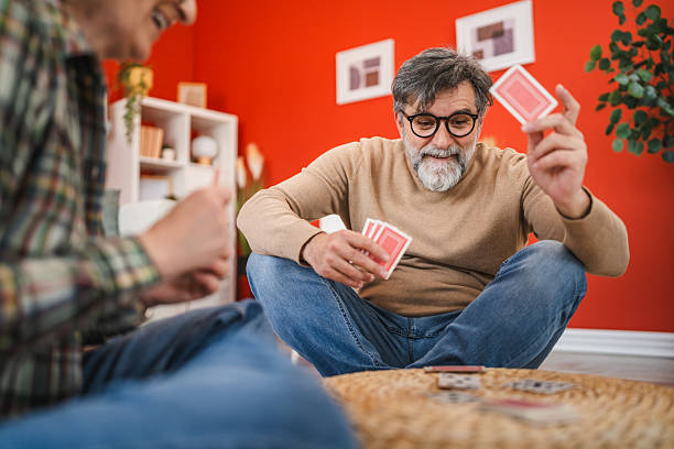 istock mature couple play cards while sit on floor and have fun at home 2205936233