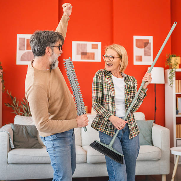 istock mature couple have fun while use cleaning tool like music instruments 2205936433