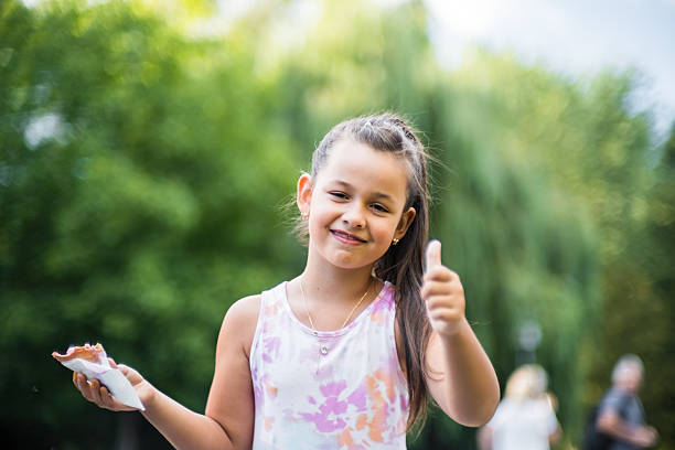 A cute child enjoys a delicious ice cream cone during the summer. Childs with ice cream on a walk in the city park. Closeup portrait of little girls eating cone ice cream.