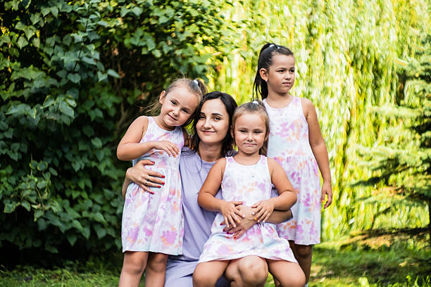 The three sisters cuddle up to their mom, their faces glowing with happiness. The little twins rest their heads on her shoulders. Their older sister gently holds them all together.