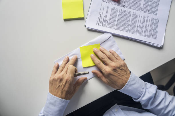 Elevated view of unidentified person's hands writing on yellow adhesive note