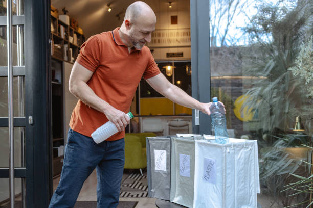 Middle age interracial couple holding recycling bin with plastic bottles at the office stressed and frustrated with hand on head, surprised and angry face