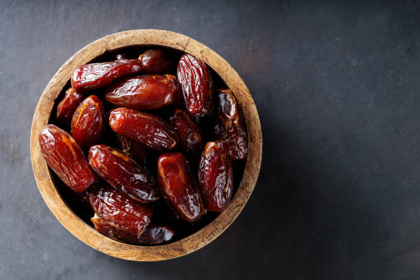 istock Dried Dates in Bowl on Dark Background, Healthy and Organic Middle Eastern Snack, Copy Space 2205940340