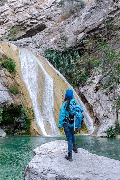 istock Female hiker admiring stunning waterfall in natural canyon setting 2205941833