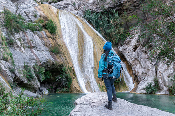 istock Female hiker admiring stunning waterfall in natural canyon setting 2205941868
