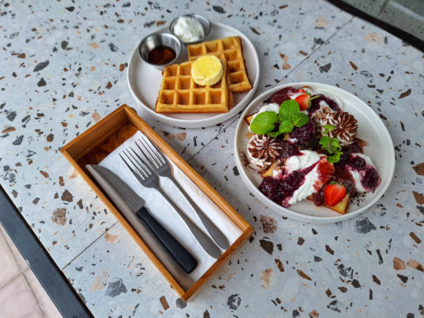 Berry Paradise Waffle With Strawberry Compote, Strawberry Fruit, Cheese Cream, Biscuit, Chocolate Powder And Fresh Mint Leaves. The Classic Waffle With Butter, Cheese Cream And Maple Syrup. Dessert Food Menu.