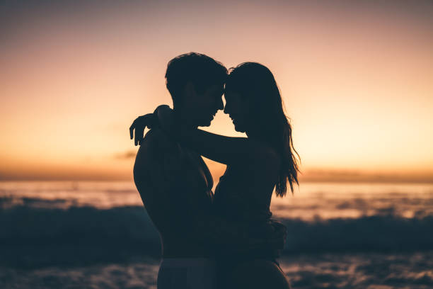 istock Couple embracing romantically in silhouette during a sunset by the ocean beach. 2205945268