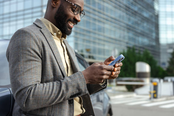 istock Businessman leaning on car while using phone on the street 2205946336