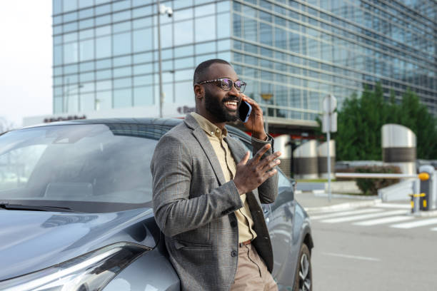 istock Businessman talking on phone while standing by his car outside a corporate building 2205946358