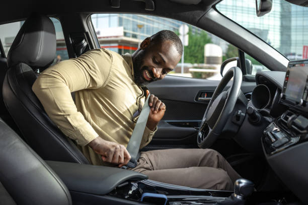 istock Smiling man fastening seatbelt inside a modern vehicle for safe driving 2205946439