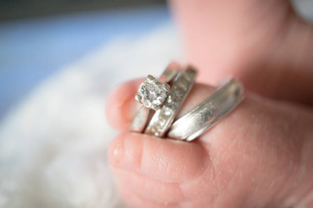 Close-up of a mother’s hand gently touching her baby’s tiny foot, with the baby slightly blurred in the background. The image highlights the emotional connection, tenderness, and soft, nurturing care between parent and child.