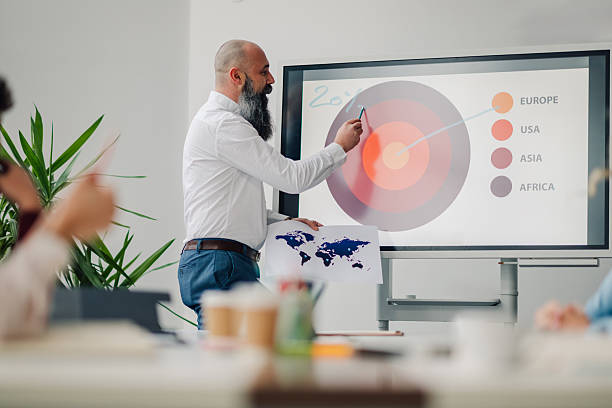 istock Businessman leading a presentation with charts and world map in modern office 2205951845