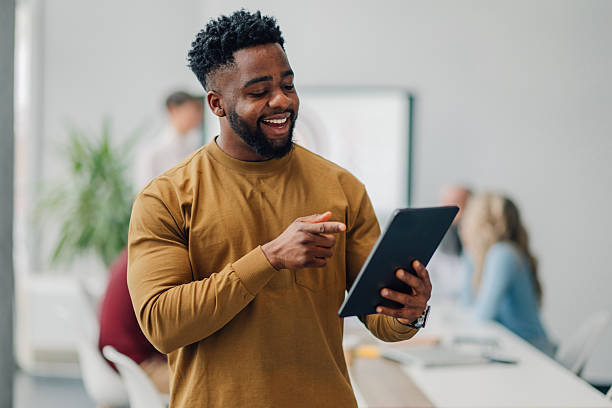 istock Young businessman pointing at digital tablet, smiling in modern office 2205951874