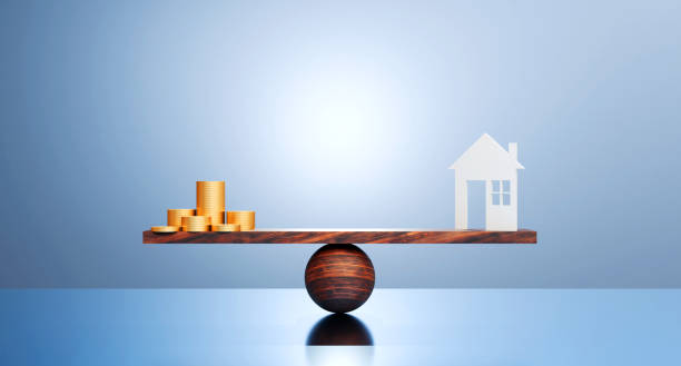 istock House and golden coin on balancing scale on blue background 2205971488