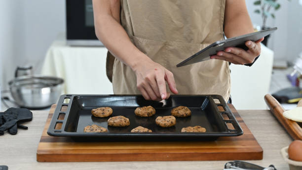 istock A man is cooking in a kitchen while holding a tablet. He is using the tablet to look up a recipe or to follow a cooking tutorial. 2205977252