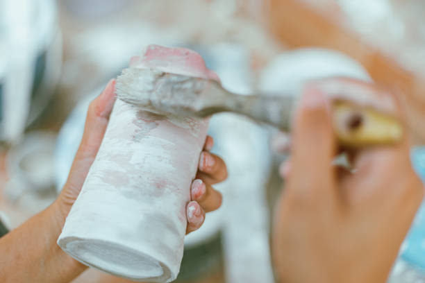 woman learning color painting her pottery at home.