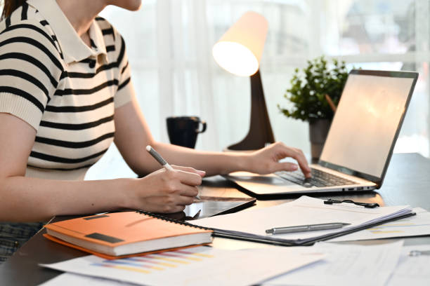 istock A woman is sitting at a desk with a laptop and a notebook. 2205977752