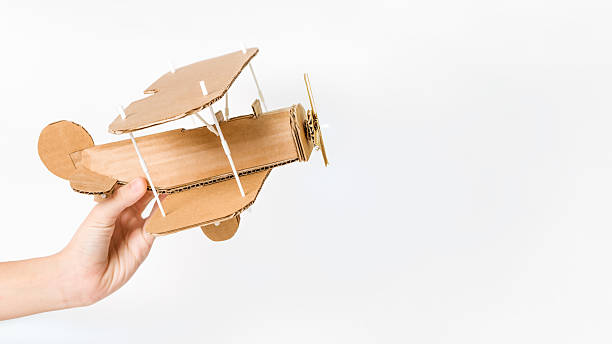 Child holding handmade cardboard biplane, DIY airplane toy. Copy space
