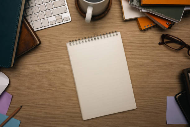istock Top view of creative workspace with blank notebook surrounded by office supplies 2205982474