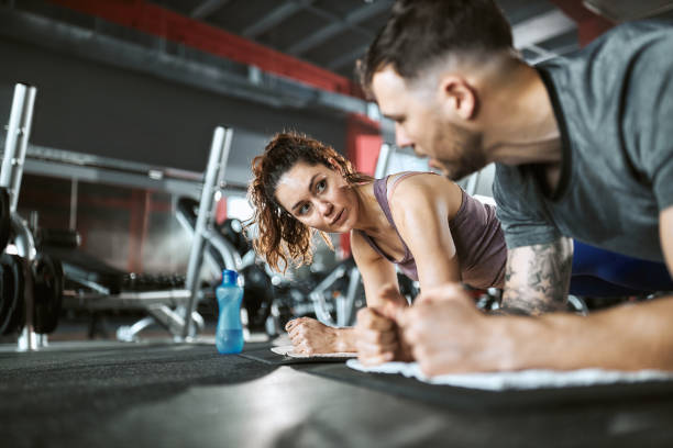 istock Athletic couple talking in plank position in a gym. 2205984017