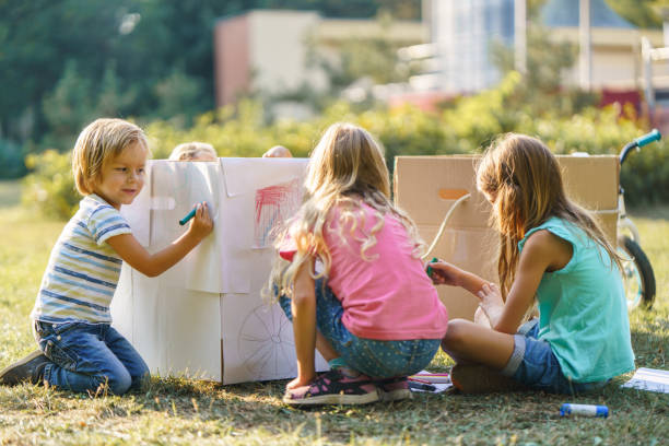 istock Children having fun drawing on carboard box in public park 2205991225