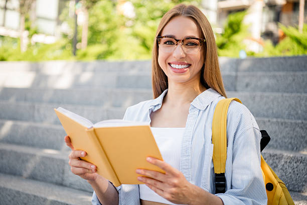 istock Young woman enjoying a sunny day, reading outdoors on urban steps 2205993878