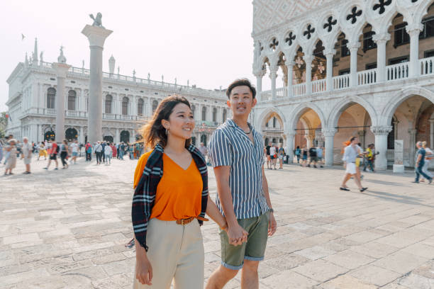 Lovely asian couple in visit to Venice, Italy. They are enjoying a beautiful day in the perfect spring weather.