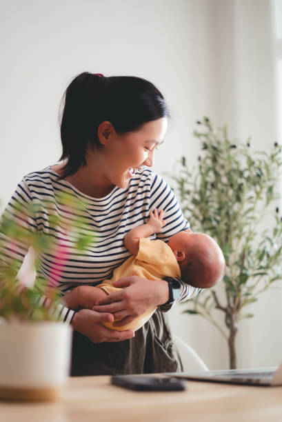 istock Asian woman carrying her baby while working at home office. 2205994685