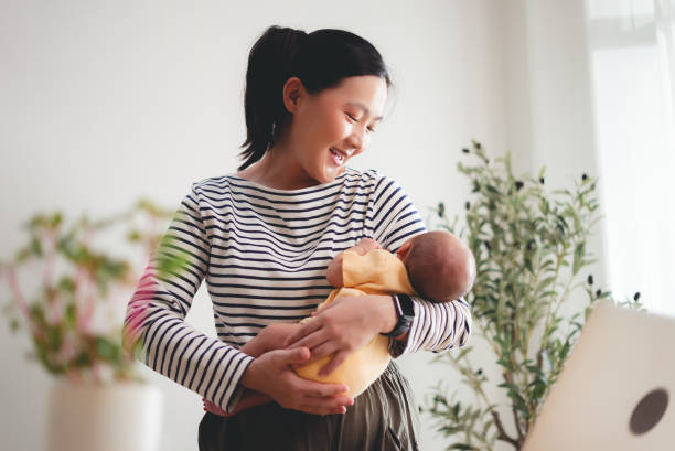 istock Asian woman carrying her baby while working at home office. 2205995235