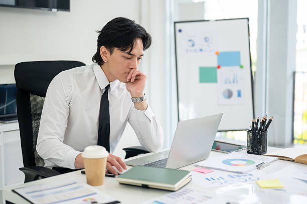 istock Businessman or male office worker is staring intently at his laptop while put a hand under chin. 2205995486