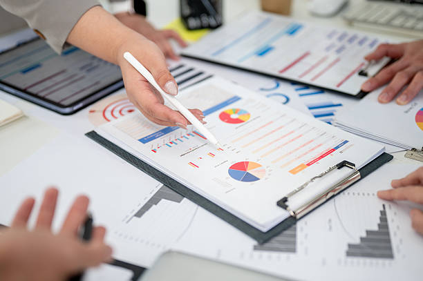 istock Close up of a hand holding stylus pointing at a clipboard over scattered documents on table. 2205995488