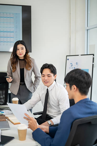 istock Businessman or male office worker is smiling while explaining a document to coworkers in a meeting. 2205995590