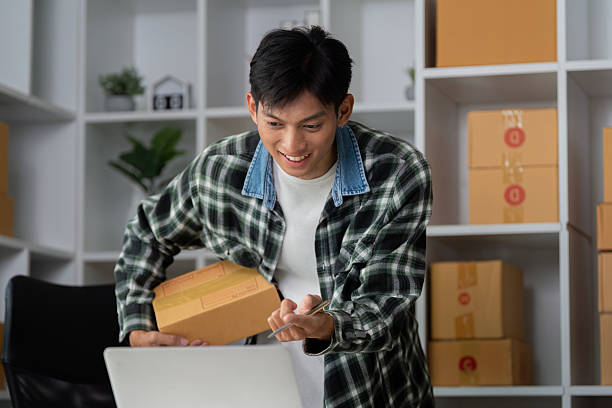 istock Entrepreneurship and Online Sales. A young man packaging products for e-commerce with a smile. 2205995936