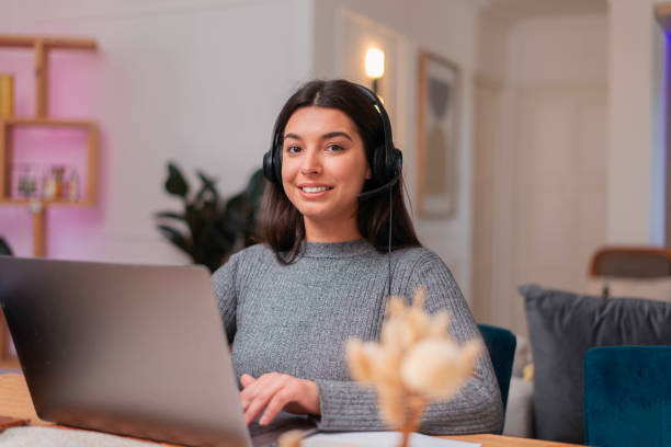 istock Young Woman Conducting Remote Business Work Wearing a Headset While Using a Laptop in a Comfortable Home Setting 2205996956