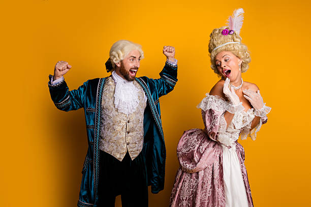 istock Two friends dressed in vintage royal costume engage actively against a yellow backdrop, showcasing historical fashion and joviality 2206000534