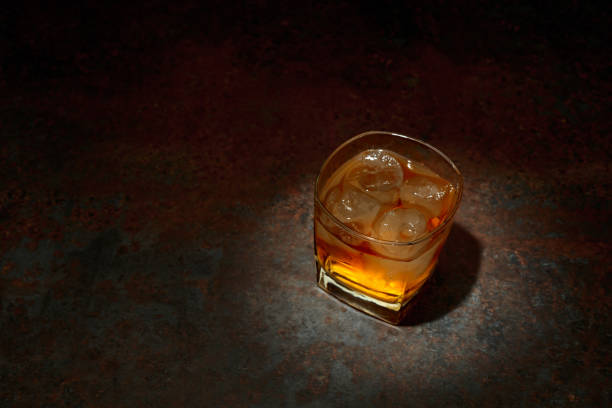istock Whiskey in a square glass with ice on a vintage background. 2206001121