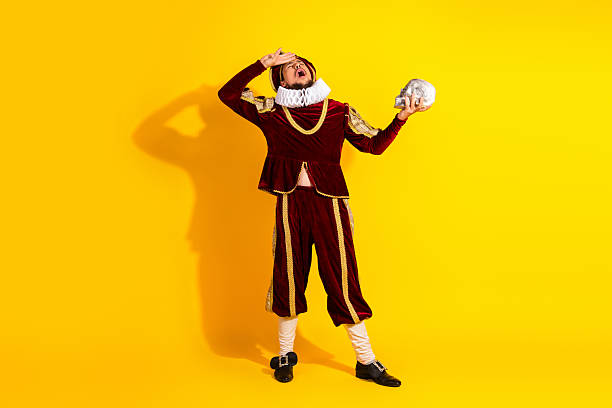 istock Actor Dressed as a Nobleman Performing Dramatically with a Skull on Yellow Background, to be or not to be 2206001369