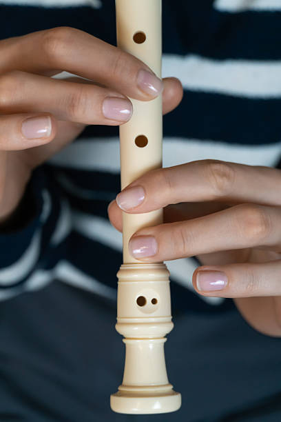 istock Close-up of hands playing a recorder flute, practicing music in a home environment, with a blurred background suggesting a comfortable and focused learning experience. Vertical photo 2206002213