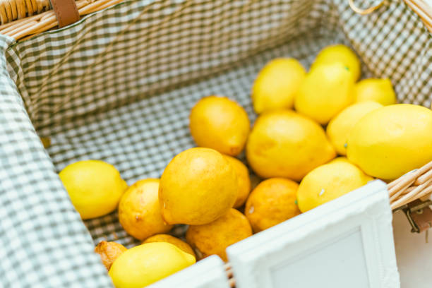 Stock photo shows a hanging basket filled with vibrant yellow lemons captures the essence of fresh citrus fruit, ideal for making homemade lemonade. The bright color and rustic presentation evoke a sunny, wholesome feel