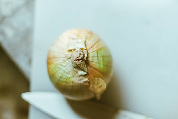 Close up fresh onions with peels on cutting board.
